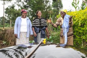 Africa: man showing two ladies biodigester system