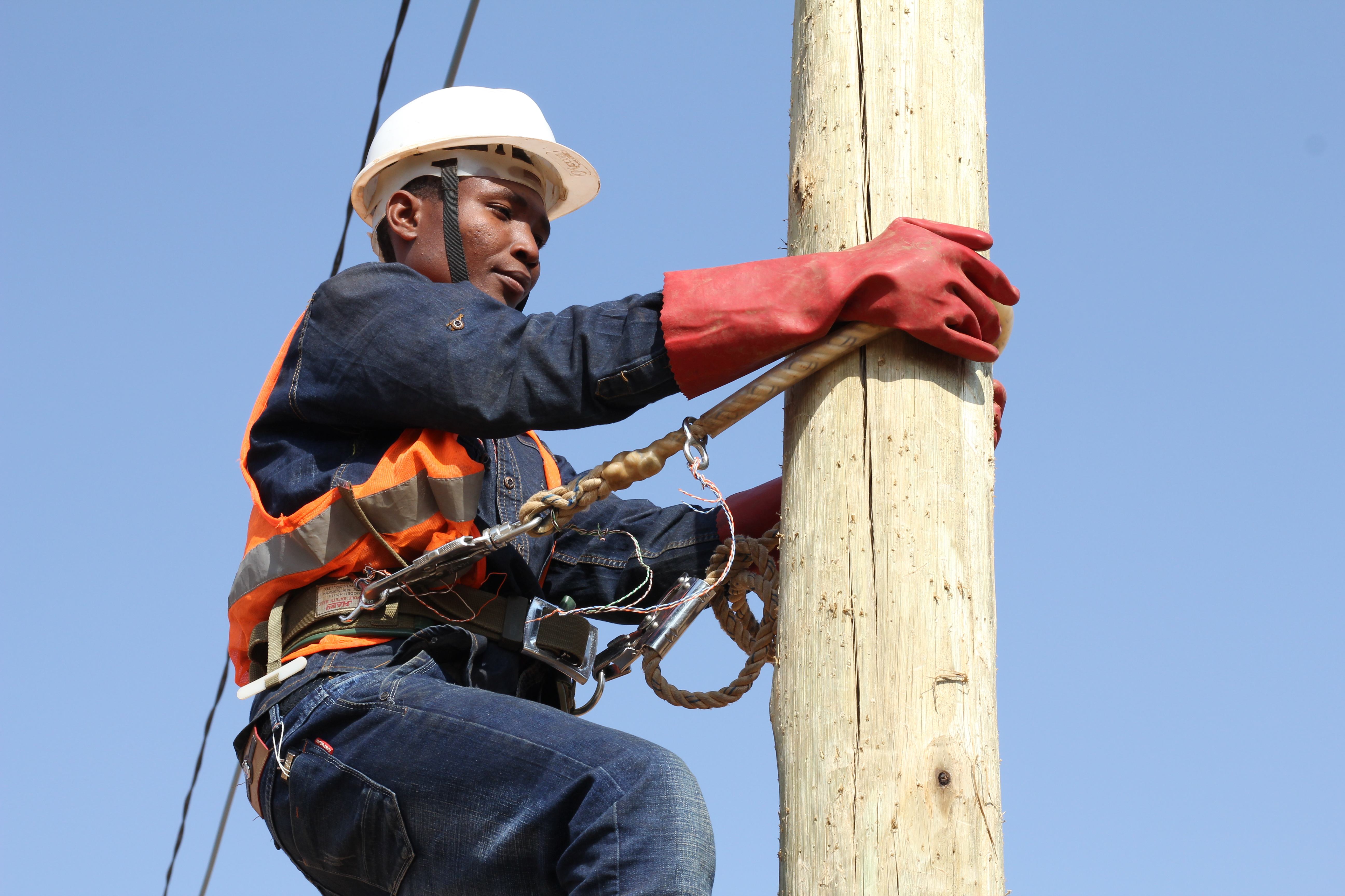 African man climbing a wooden pole