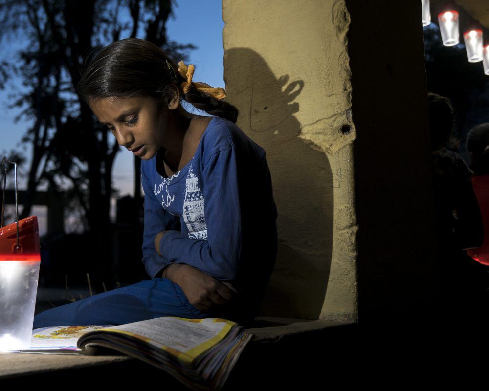 Young Indian girl reading by solar lantern