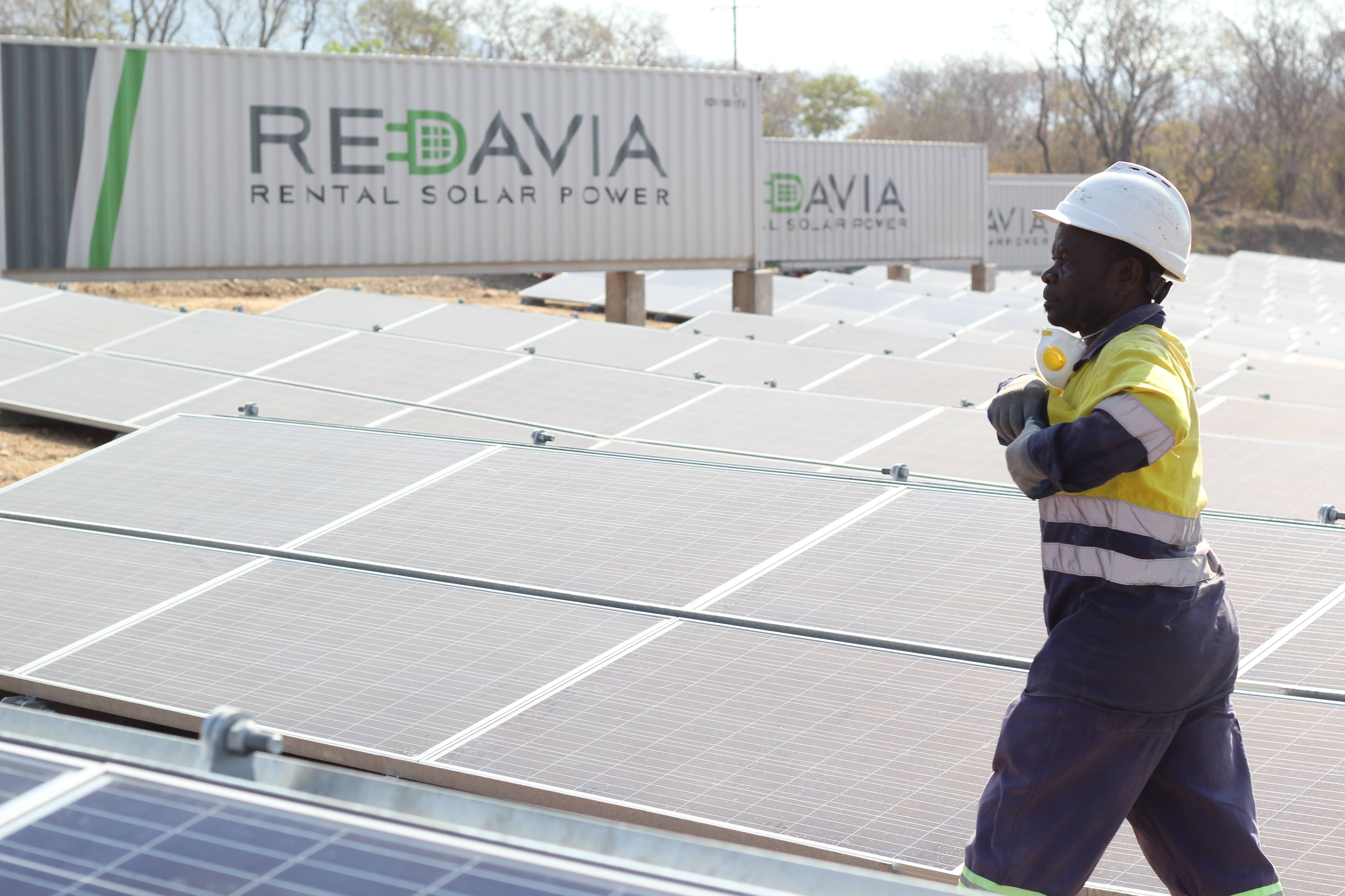 Redavia solar farm with male engineer walking between panels