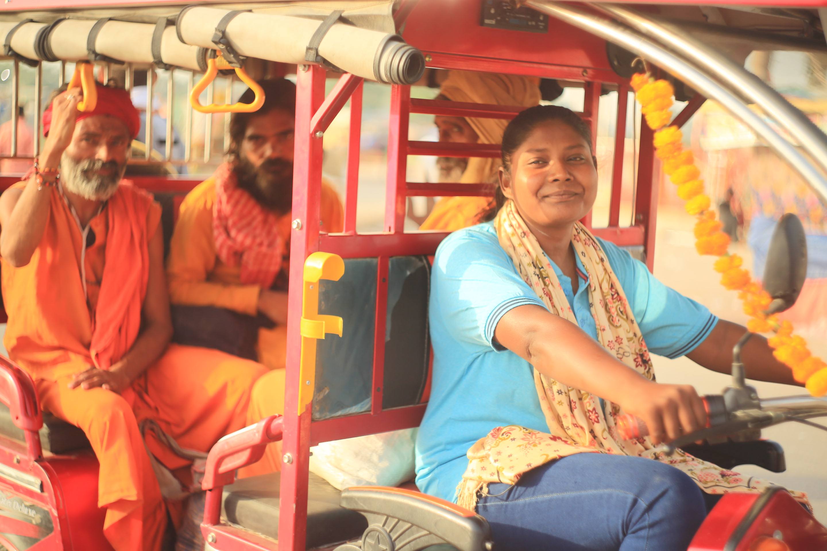 Indian lady driving tuk tuk with two male passengers