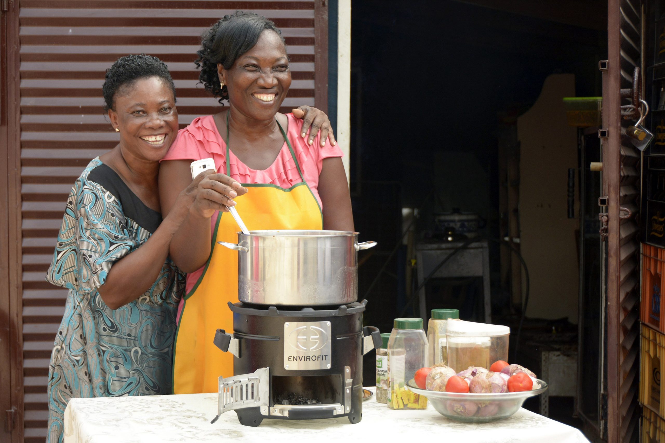 Tw ladies stirring pot on Envirofit stove