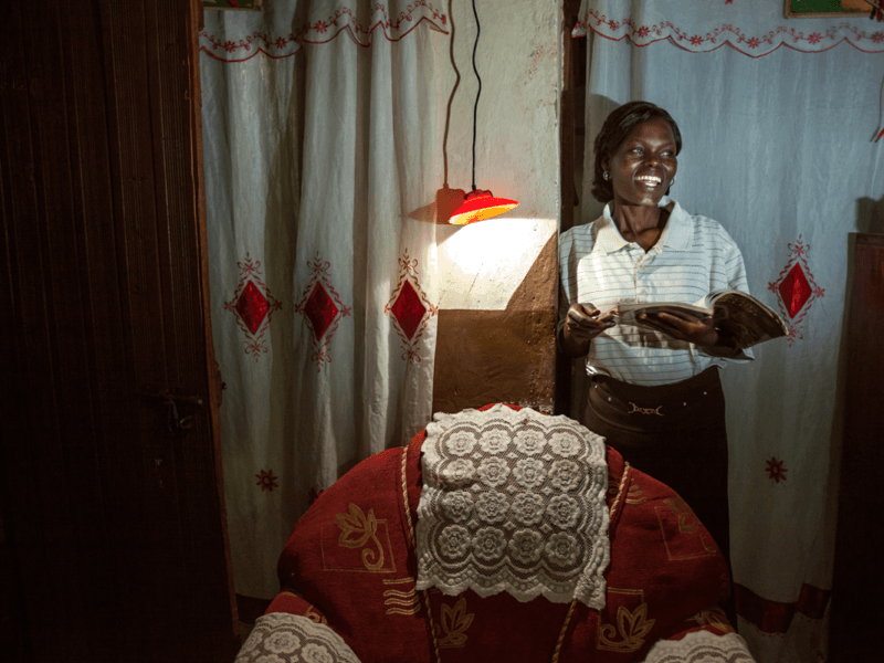 lady standing reading by solar light - Africa