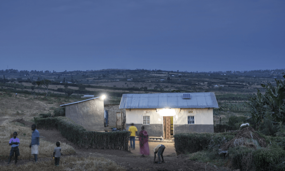 Solar lit house at dusk in village with people