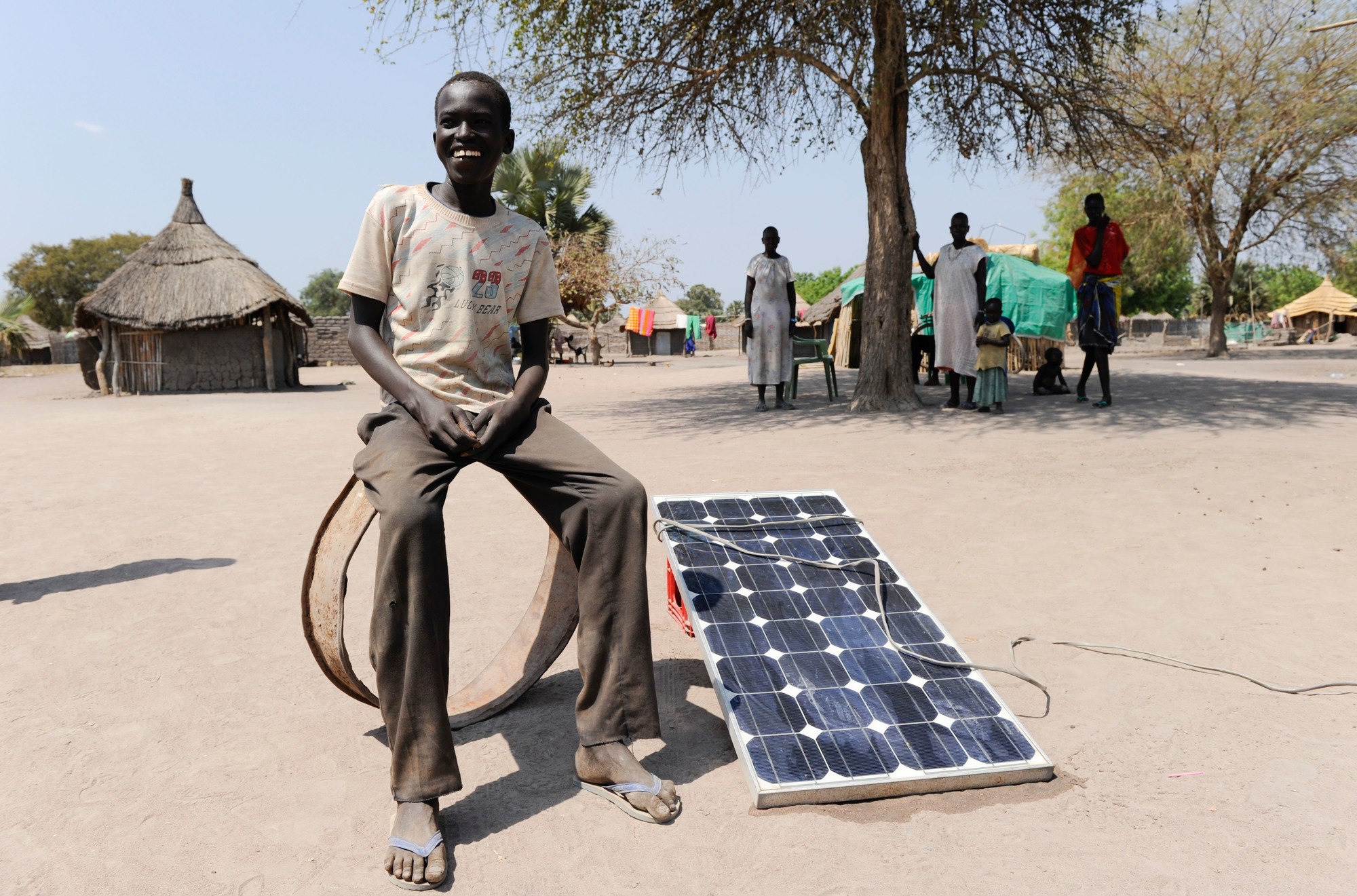 Young African man sitting on some sort of ring next to a solar panel
